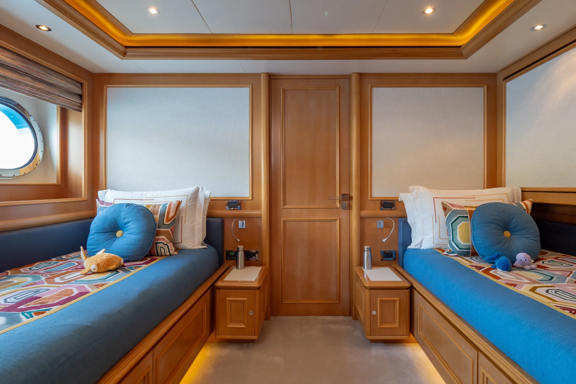Twin guest cabin in warm wood with portholes to the sea